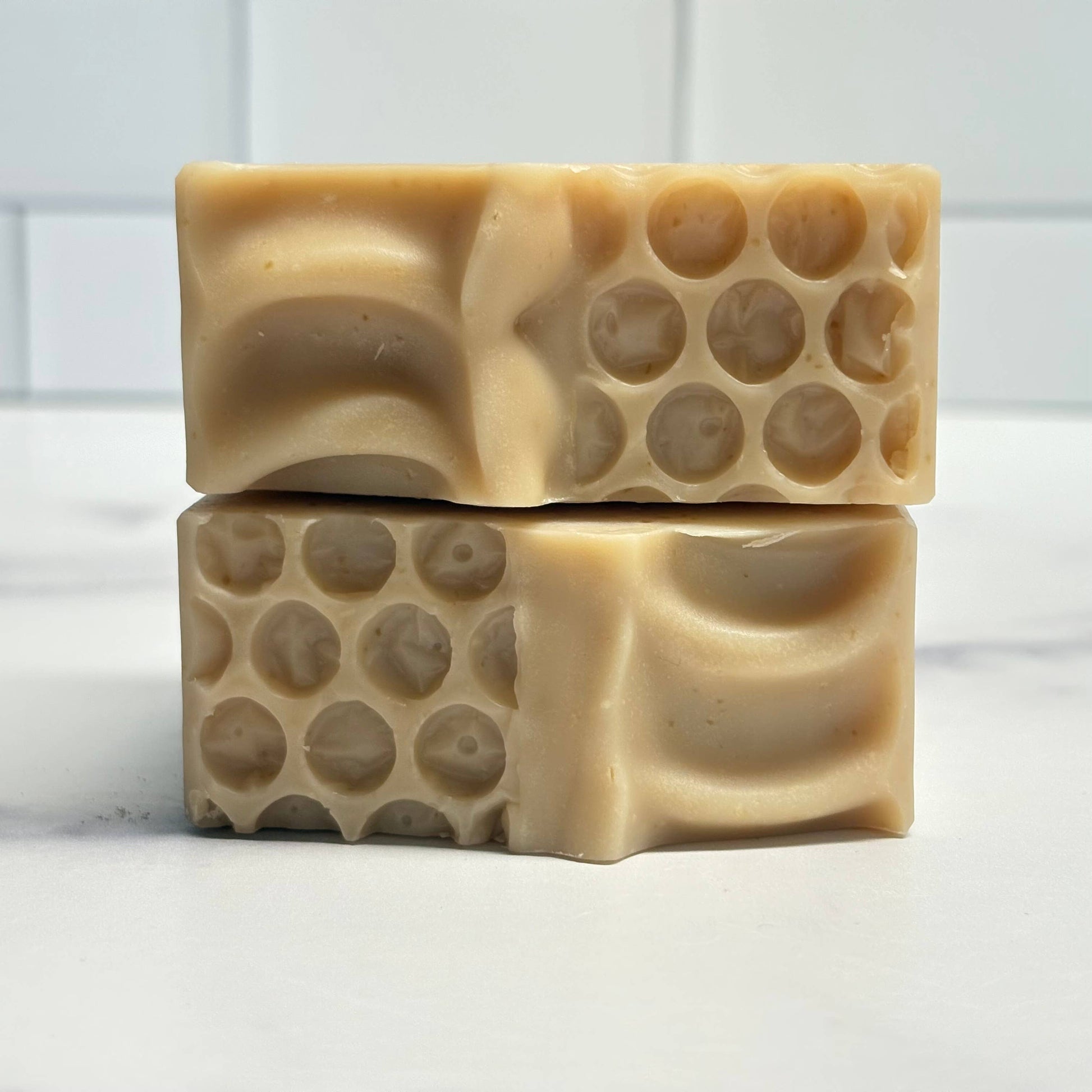 Two bars of soap with a honeycomb pattern on a white background