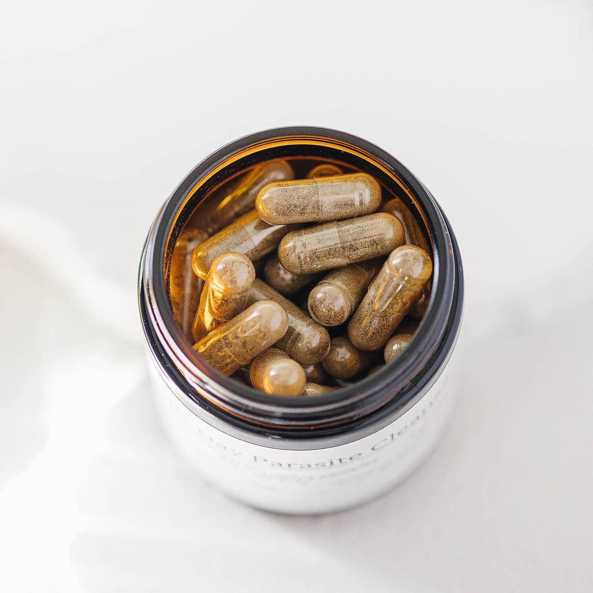 Supplement capsules in a glass container on a white background