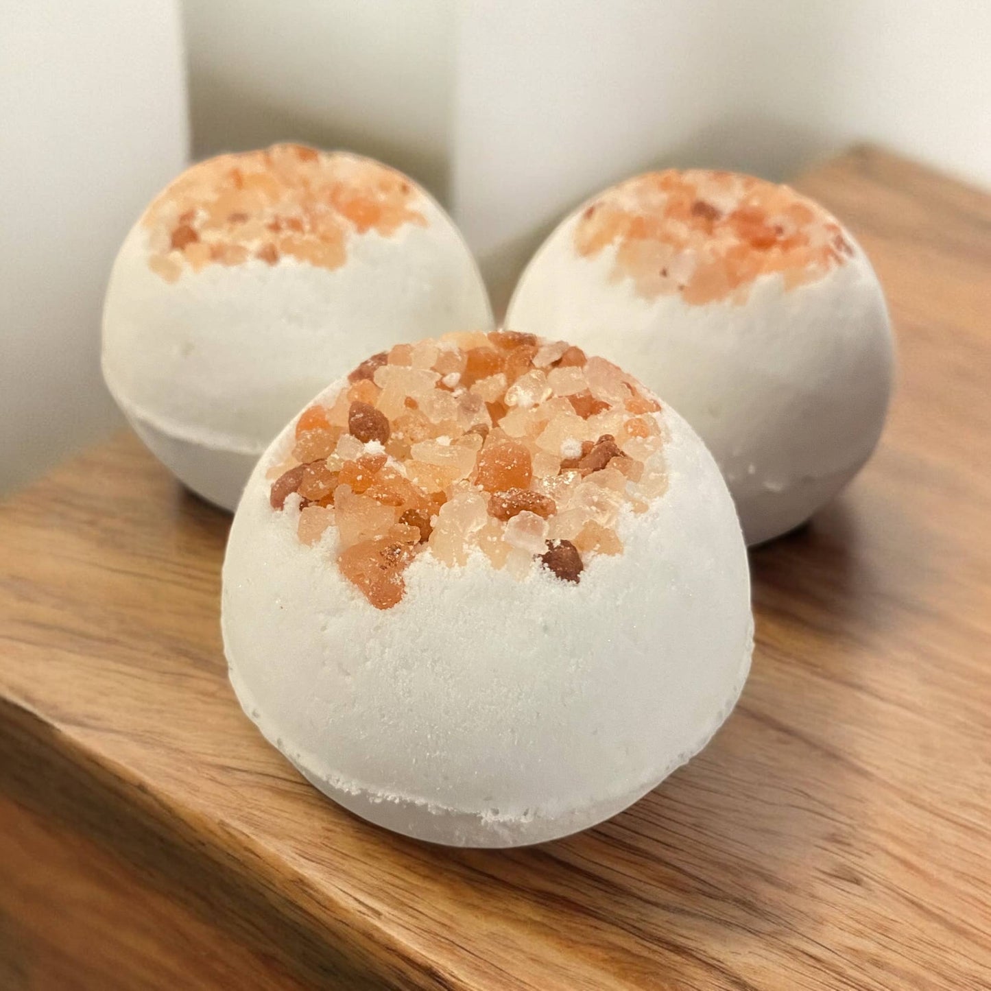 Three bath bombs with a textured top on a wooden surface