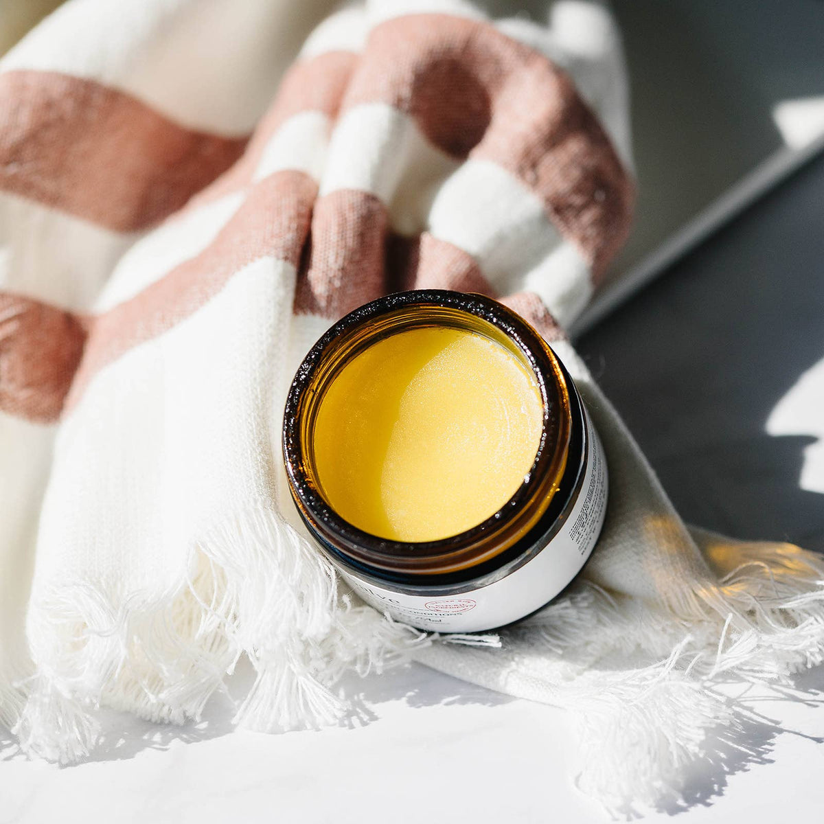 Jar of yellow cream with a hand wrapped in bandages in the background