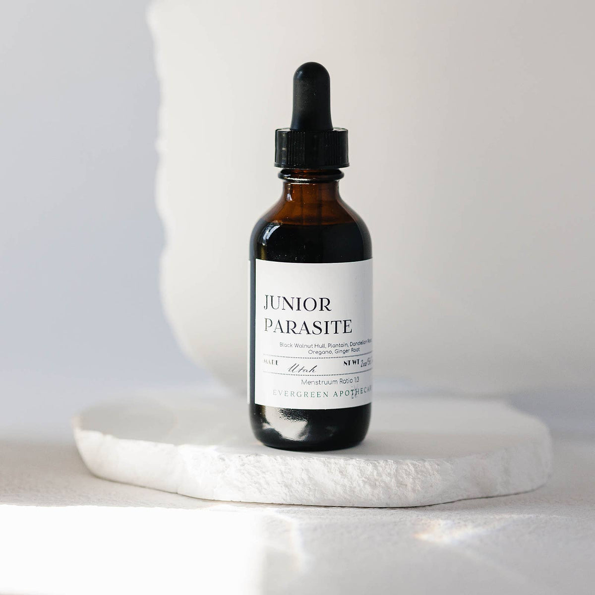 Bottle of 'Junior Parasite' on a white surface with a neutral background