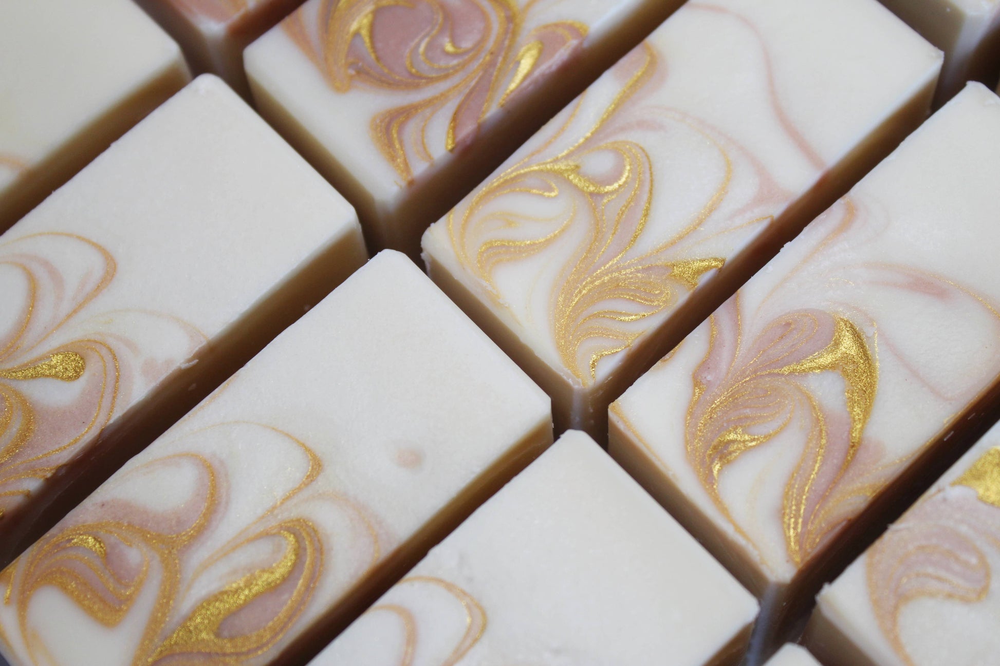 Marble-patterned soap bars with gold accents arranged in a grid.
