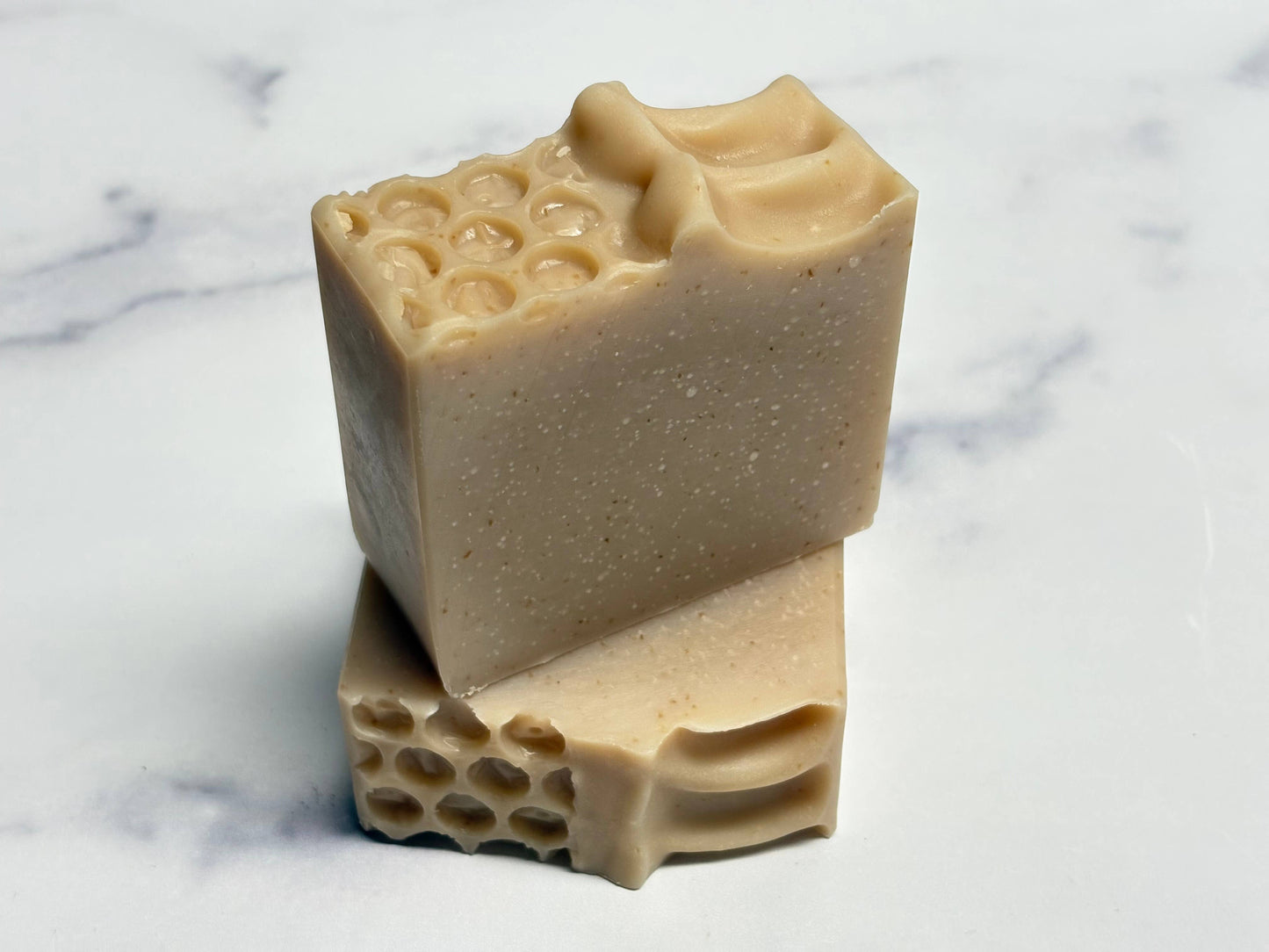 Two bars of soap with honeycomb design on a marble surface