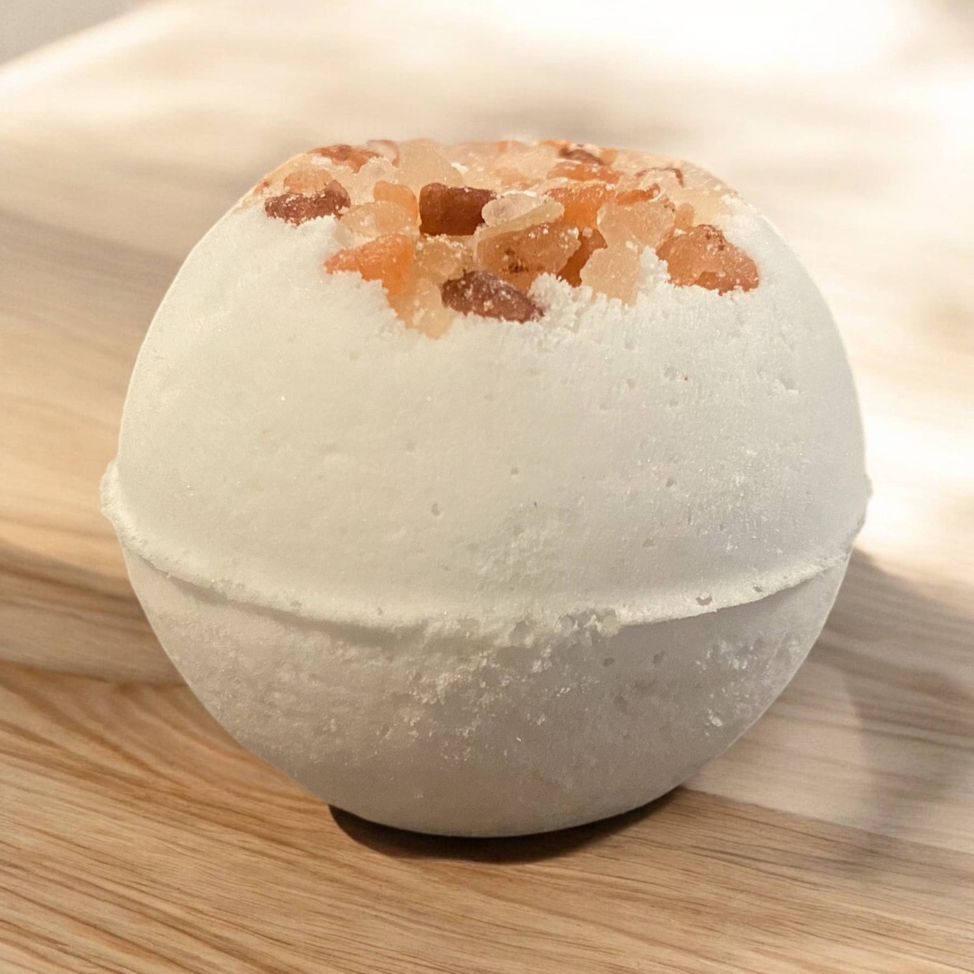 Bath bomb with visible salt crystals on a wooden surface