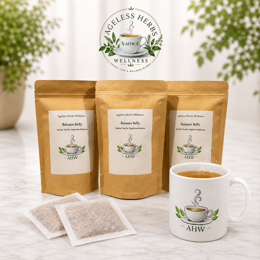 Three stand-up pouches of Ageless Herbs Wellness Balance Belly tea, two individual tea bags, and a white ceramic mug filled with tea, arranged on a light marble surface with a blurred green plant in the background. The Ageless Herbs Wellness logo is displayed at the top center.