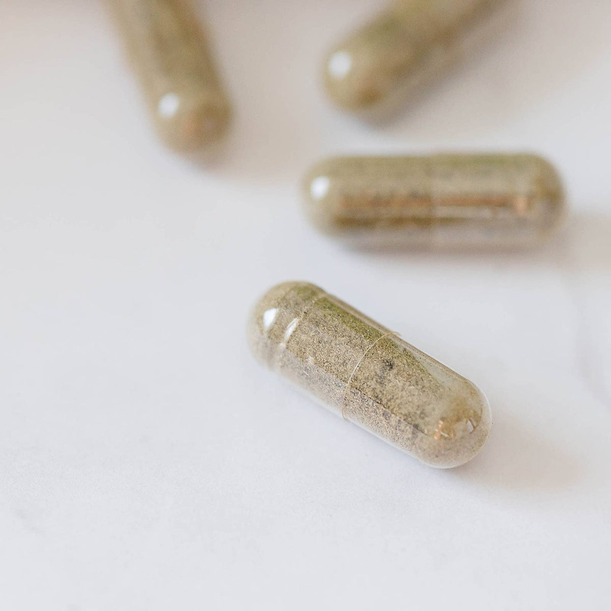Herbal supplement capsules on a light surface