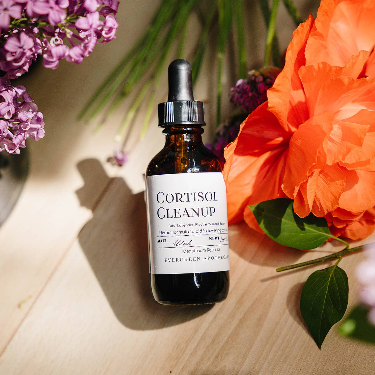 Bottle of 'Cortisol Cleanup' with flowers on a wooden surface