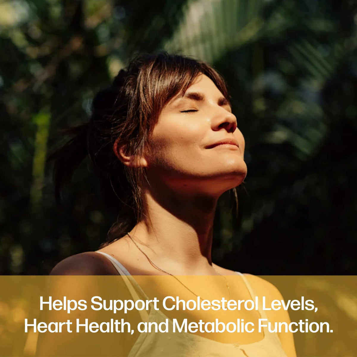 A woman with her eyes closed and head tilted back, bathed in warm sunlight against a dark green foliage background. A translucent yellow banner at the bottom contains white text reading: 'Helps Support Cholesterol Levels, Heart Health, and Metabolic Function.