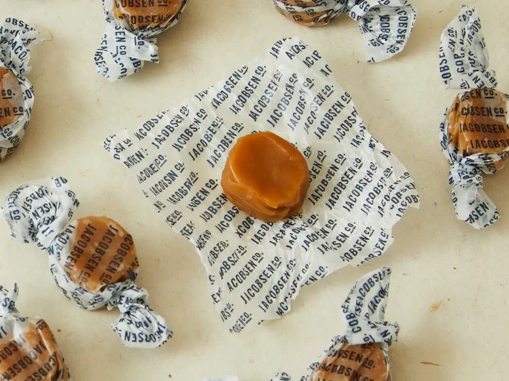 Caramel candies with paper wrappings on a textured surface