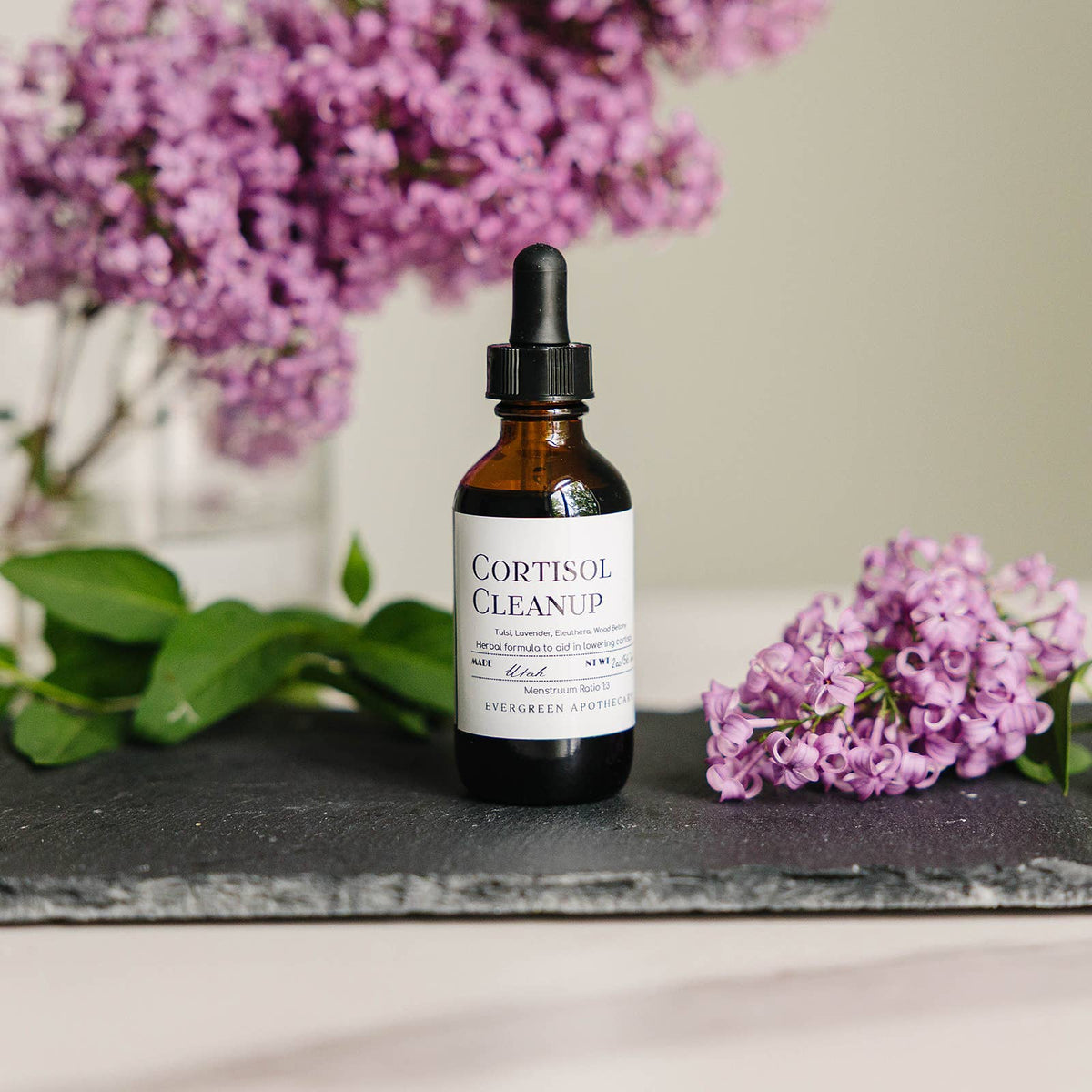 Bottle of 'Cortisol Cleanup' with purple flowers in the background