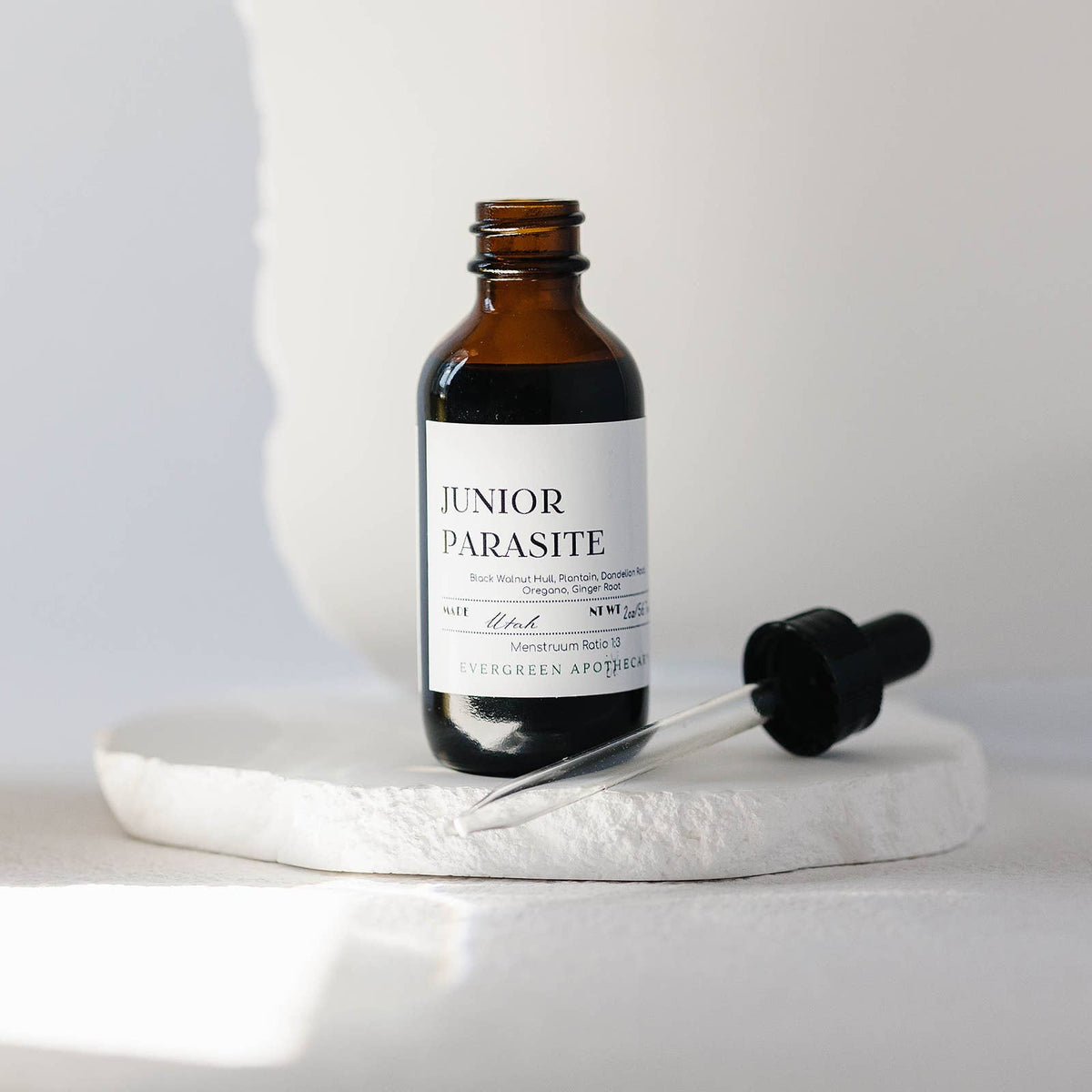 Amber glass bottle with dropper labeled 'Junior Parasite' on a white surface.